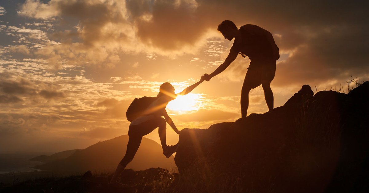 Climbers helping each other reach the summit